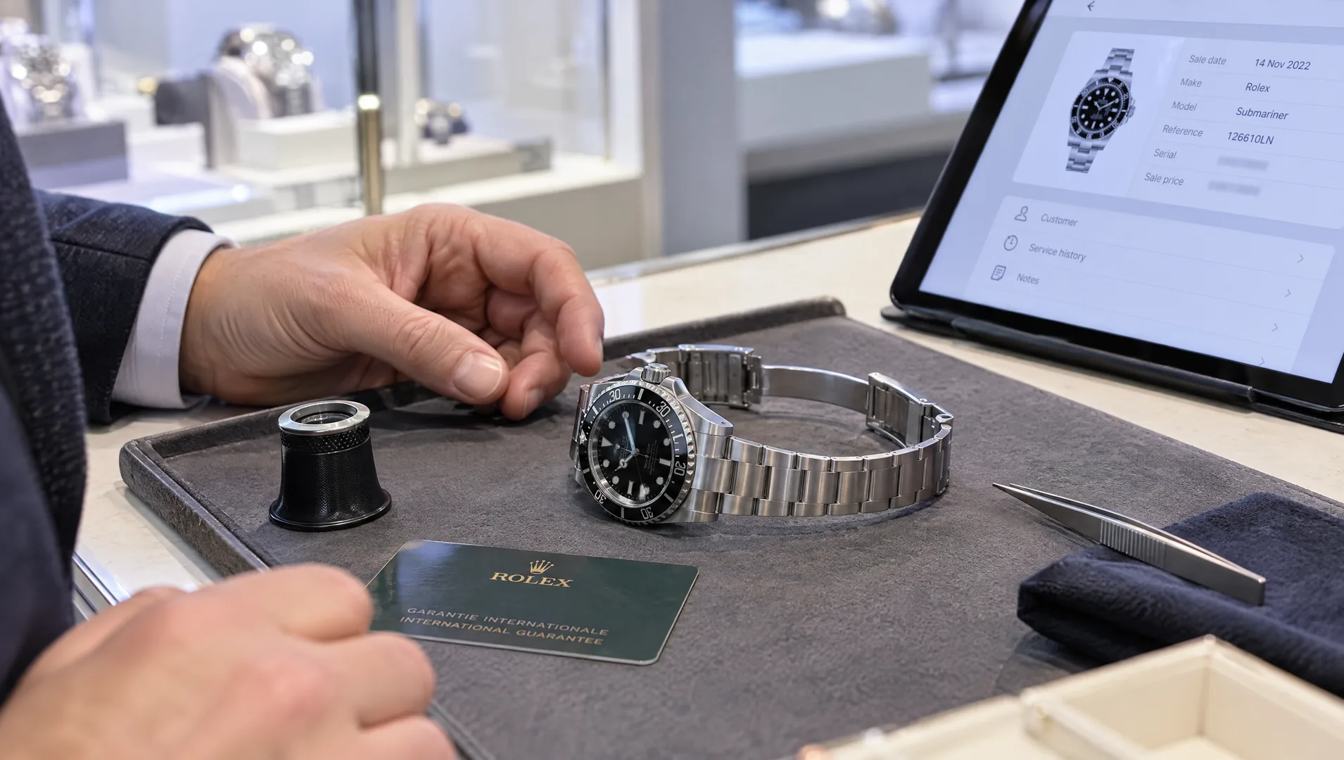 Watch dealer comparing a previously sold watch with its original digital record before buying it back.