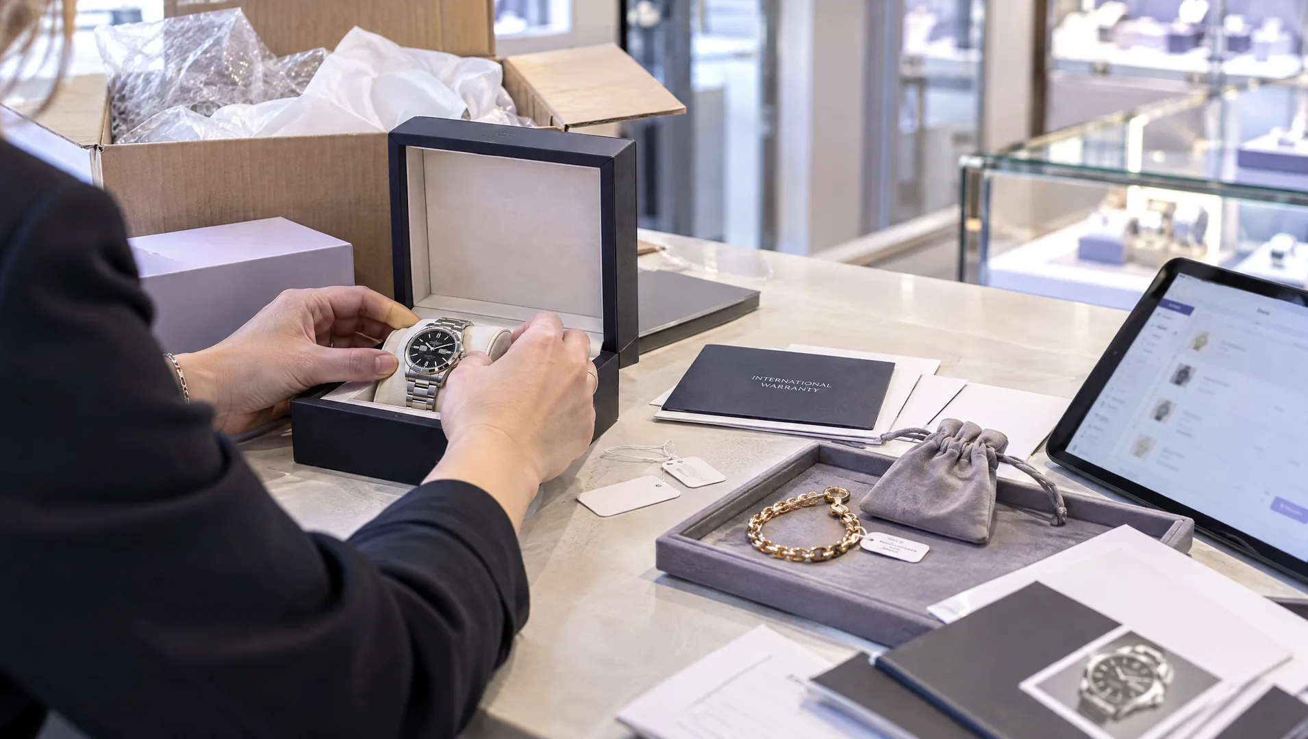 Jeweller recording watch and jewellery purchase details at the counter.